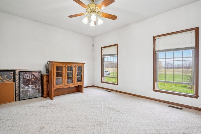 unfurnished room with ceiling fan, baseboards, carpet flooring, and visible vents