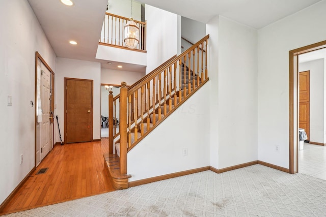 carpeted entrance foyer with visible vents, baseboards, recessed lighting, a notable chandelier, and stairway