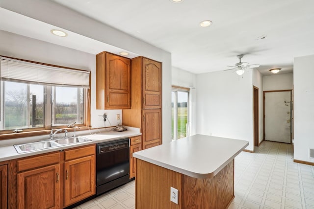 kitchen with dishwasher, brown cabinetry, light floors, and a sink