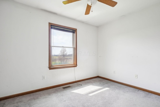 carpeted empty room with baseboards, visible vents, and ceiling fan