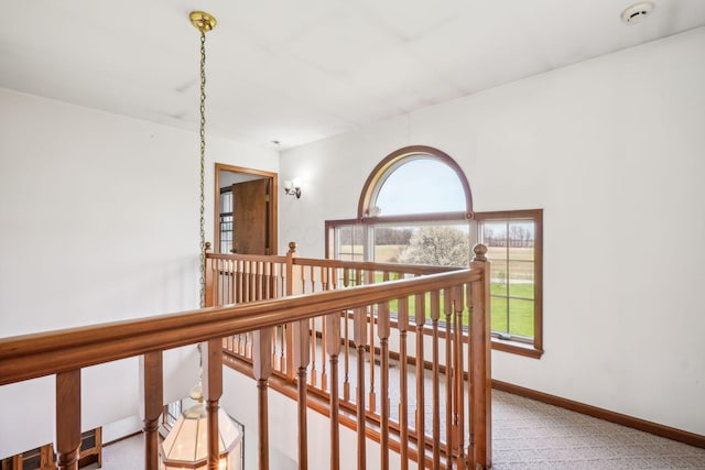 hallway with baseboards, an upstairs landing, and carpet