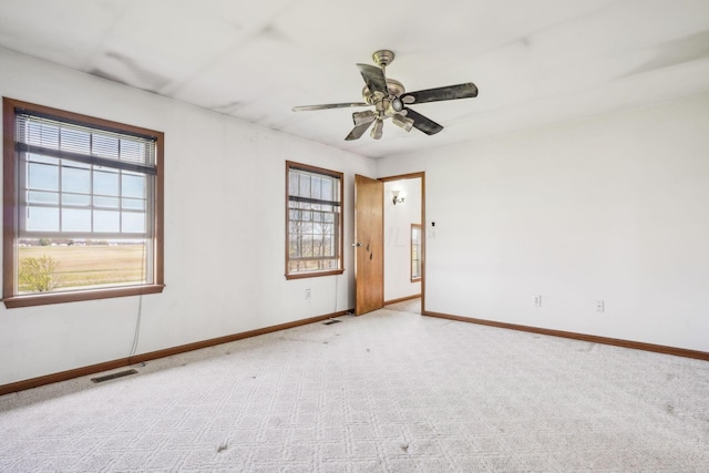empty room with ceiling fan, baseboards, carpet floors, and visible vents