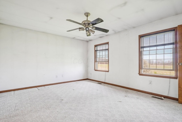 empty room with ceiling fan, carpet floors, visible vents, and baseboards
