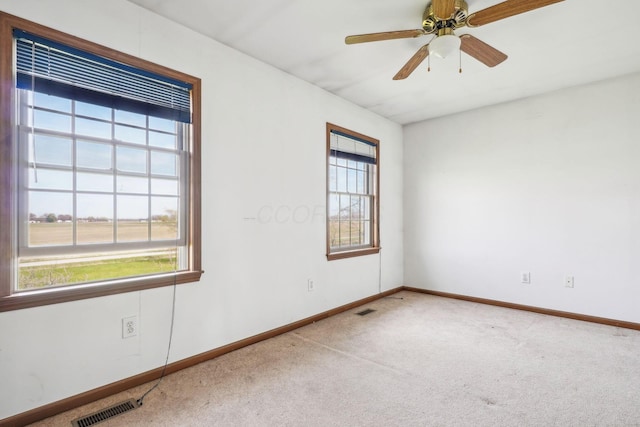 carpeted empty room featuring ceiling fan, baseboards, and visible vents