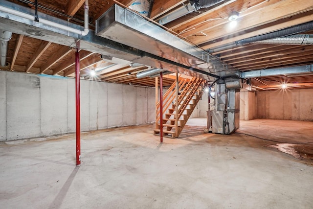 unfinished basement featuring heating unit and stairway