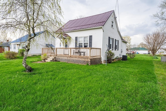 back of property featuring a lawn, a wooden deck, cooling unit, and metal roof
