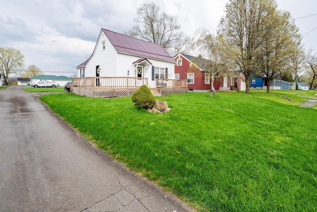 view of front of property with a wooden deck, metal roof, and a front yard