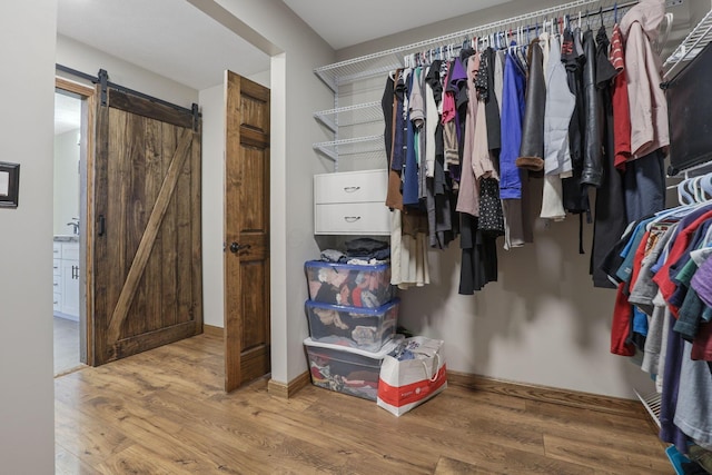 spacious closet with wood finished floors and a barn door
