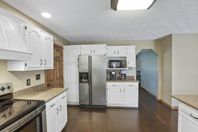 kitchen with premium range hood, dark wood-type flooring, light stone countertops, appliances with stainless steel finishes, and white cabinetry