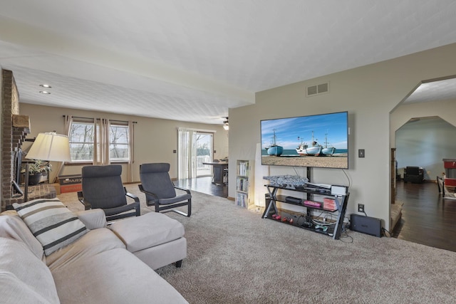 carpeted living room featuring visible vents and arched walkways