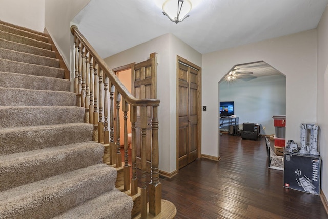 interior space featuring a ceiling fan, stairs, hardwood / wood-style floors, arched walkways, and baseboards