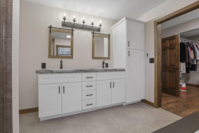 bathroom with baseboards, tile patterned floors, a sink, and double vanity