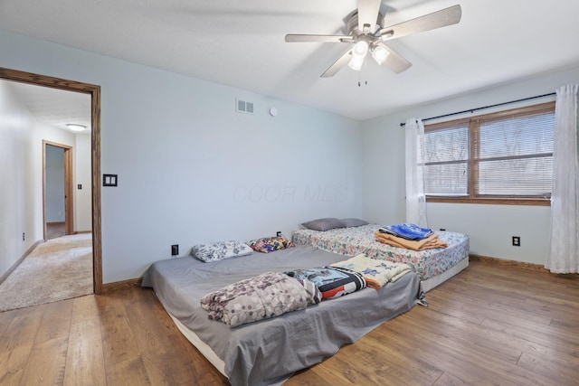 bedroom featuring baseboards, visible vents, a ceiling fan, and hardwood / wood-style flooring