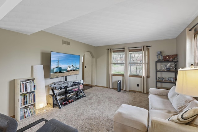 carpeted living room with baseboards, visible vents, and arched walkways