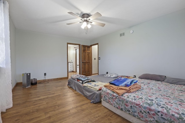 bedroom featuring baseboards, a ceiling fan, wood finished floors, and visible vents