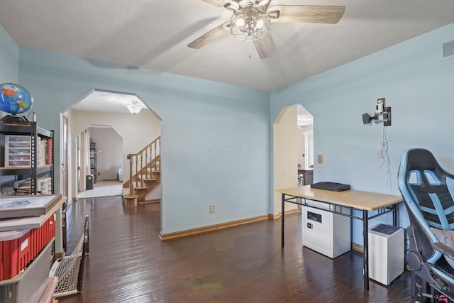 office area with dark wood finished floors, arched walkways, a ceiling fan, and baseboards