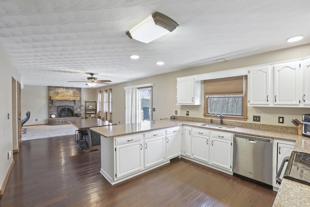 kitchen featuring a peninsula, stainless steel dishwasher, a sink, and a healthy amount of sunlight