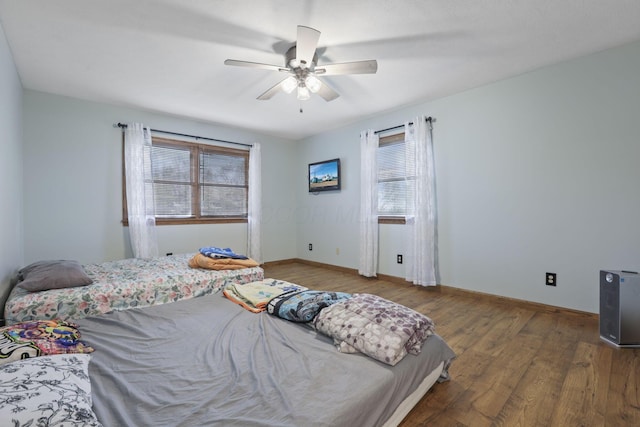bedroom featuring wood finished floors, baseboards, and ceiling fan