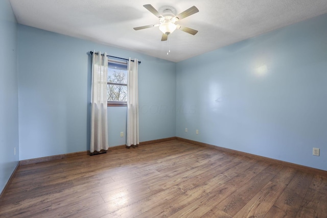 spare room featuring baseboards, a ceiling fan, and wood finished floors
