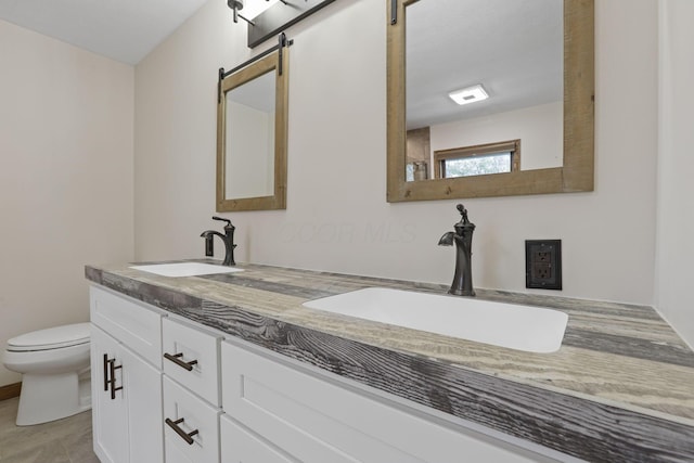 bathroom with toilet, a sink, and double vanity