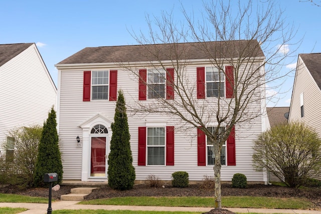colonial house featuring a shingled roof