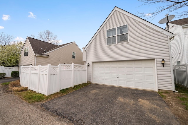 view of home's exterior with a garage, fence, and driveway