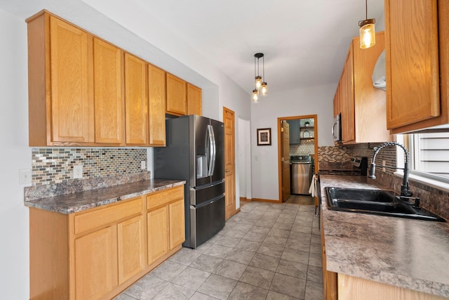 kitchen featuring a sink, stainless steel appliances, baseboards, decorative light fixtures, and decorative backsplash
