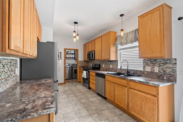 kitchen featuring backsplash, appliances with stainless steel finishes, dark countertops, washing machine and dryer, and a sink
