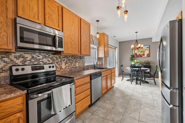 kitchen with dark countertops, a notable chandelier, a sink, stainless steel appliances, and tasteful backsplash