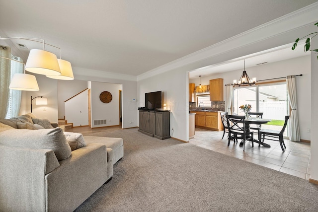 living room with crown molding, baseboards, a notable chandelier, and light carpet