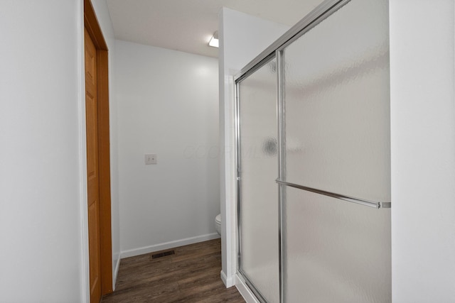 bathroom featuring toilet, baseboards, a shower stall, wood finished floors, and visible vents