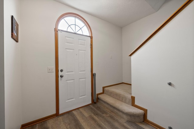entrance foyer featuring baseboards, dark wood finished floors, and stairs