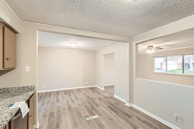 unfurnished dining area with a textured ceiling, light wood-type flooring, ceiling fan, and baseboards