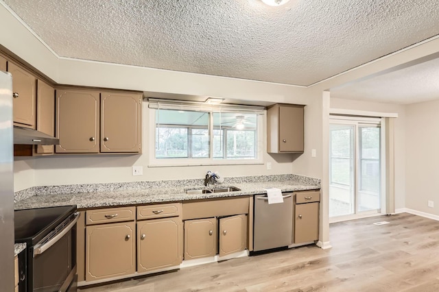 kitchen with appliances with stainless steel finishes, a sink, under cabinet range hood, a textured ceiling, and light wood-style floors