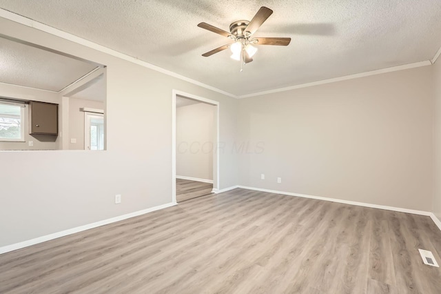 unfurnished room with a textured ceiling, wood finished floors, a ceiling fan, baseboards, and crown molding