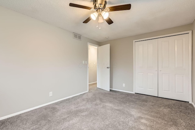 unfurnished bedroom featuring carpet floors, baseboards, a closet, a textured ceiling, and a ceiling fan