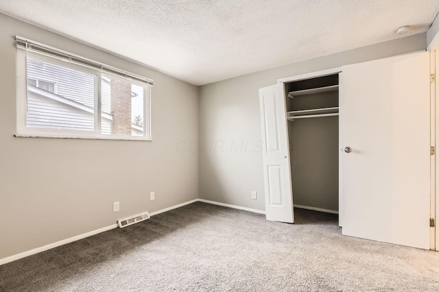 unfurnished bedroom with carpet floors, a textured ceiling, baseboards, and a closet