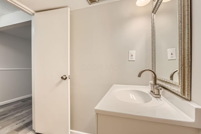 bathroom with wood finished floors, vanity, and baseboards
