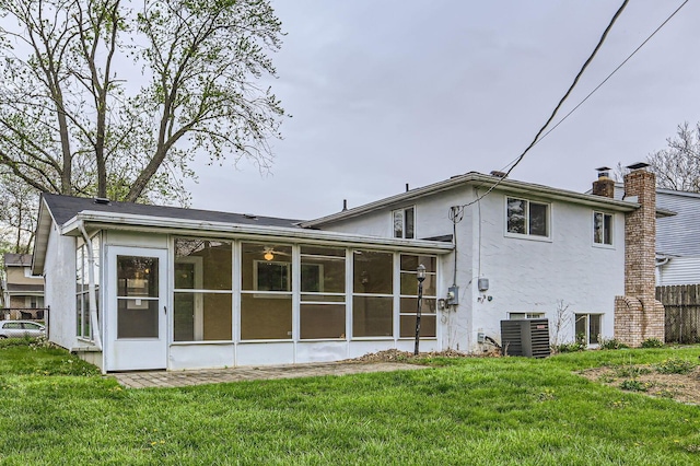 back of property featuring central AC, stucco siding, a sunroom, and a chimney