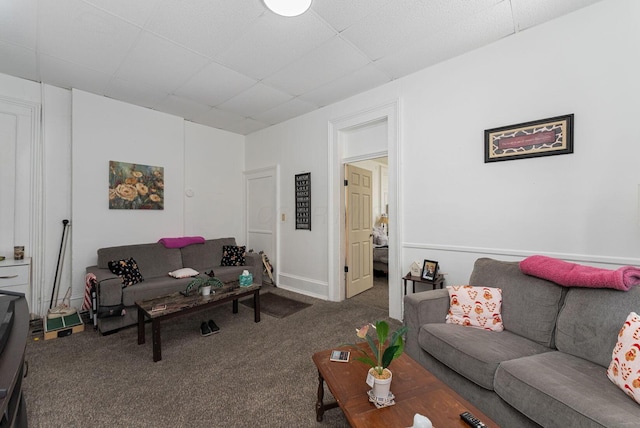 living room with a drop ceiling and carpet