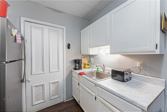 kitchen featuring white cabinetry, a sink, light countertops, and freestanding refrigerator