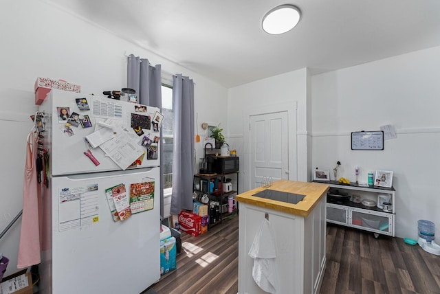 kitchen featuring butcher block counters, freestanding refrigerator, white cabinetry, and dark wood-style flooring
