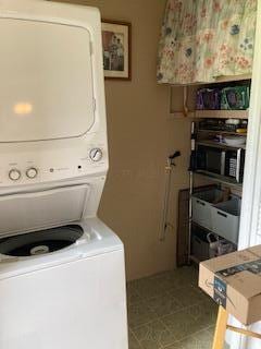 clothes washing area with stacked washing maching and dryer and laundry area