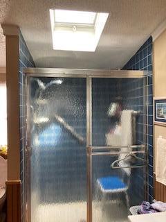 full bathroom with a shower stall, vaulted ceiling, toilet, and a textured ceiling