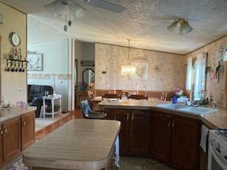kitchen with a center island, range with gas cooktop, a ceiling fan, and light countertops