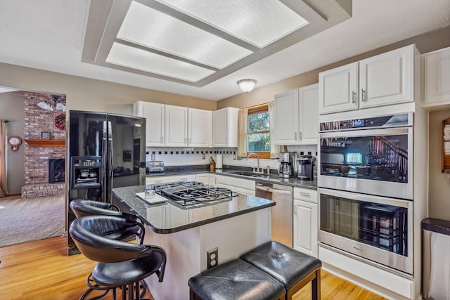 kitchen with a sink, white cabinets, a breakfast bar, and stainless steel appliances