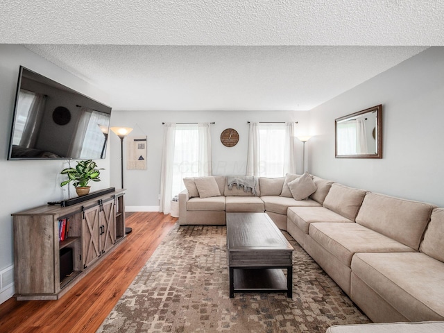living area with baseboards, wood finished floors, and a textured ceiling