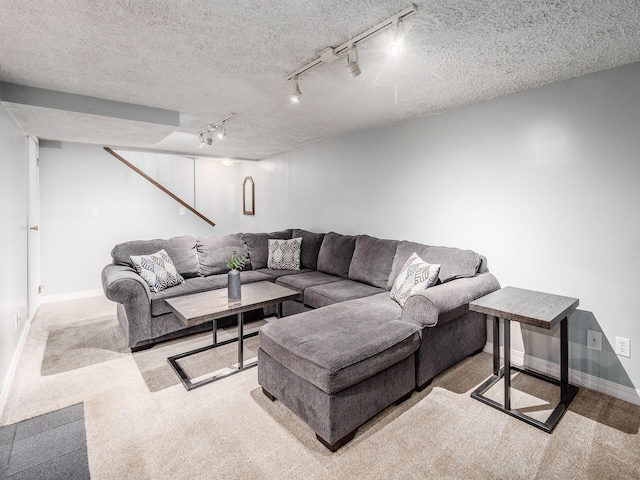 carpeted living area with baseboards, a textured ceiling, and rail lighting