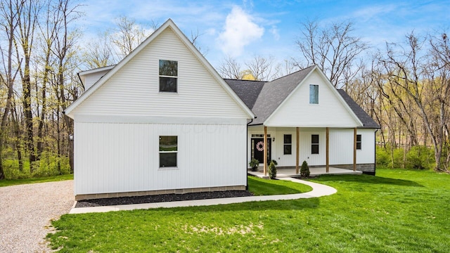 back of property with a porch, a shingled roof, and a yard