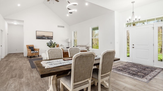 dining space with high vaulted ceiling, light wood finished floors, a notable chandelier, visible vents, and recessed lighting